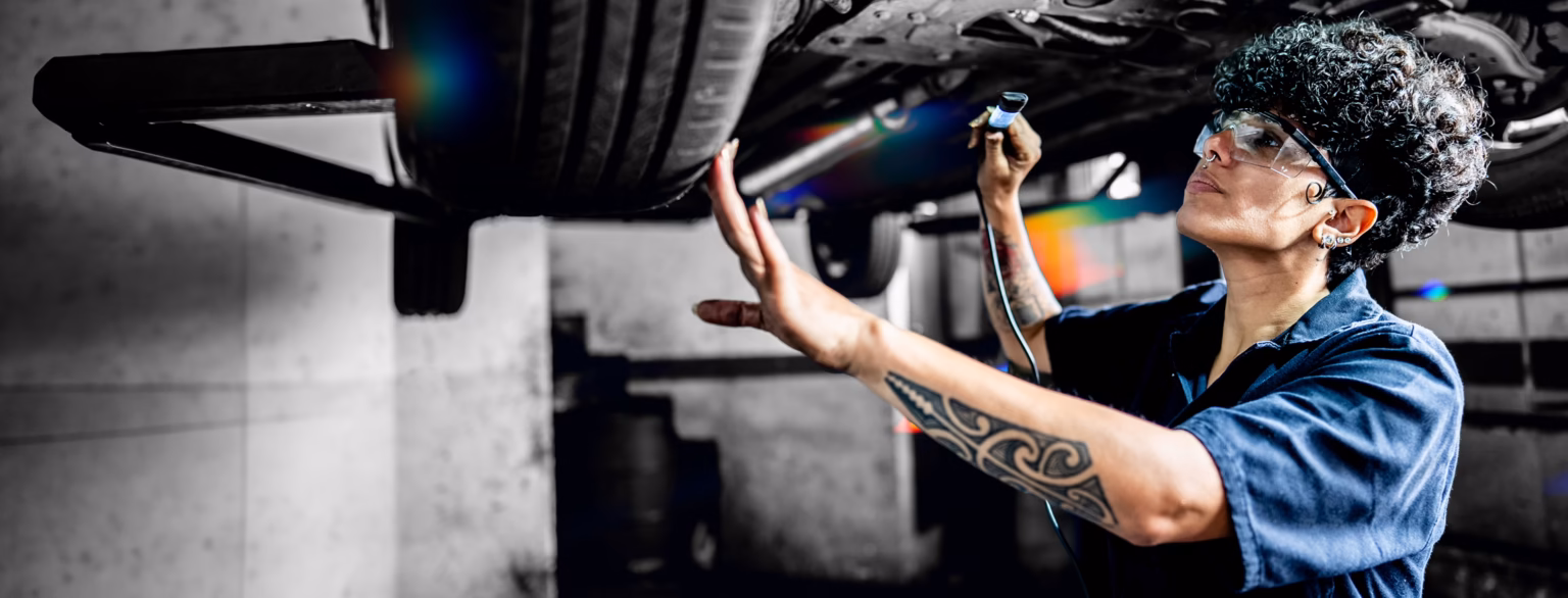Mechanic inspecting underside of a car with a flashlight